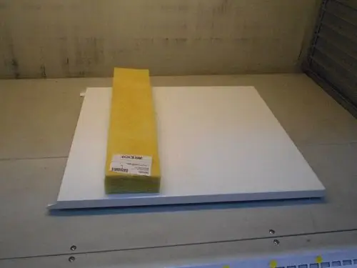 Weißes, rechteckiges Plastikteil auf einem Tisch, daneben ein gelbes Isoliermaterial. Das Produkt gehört zur Marke Remeha.